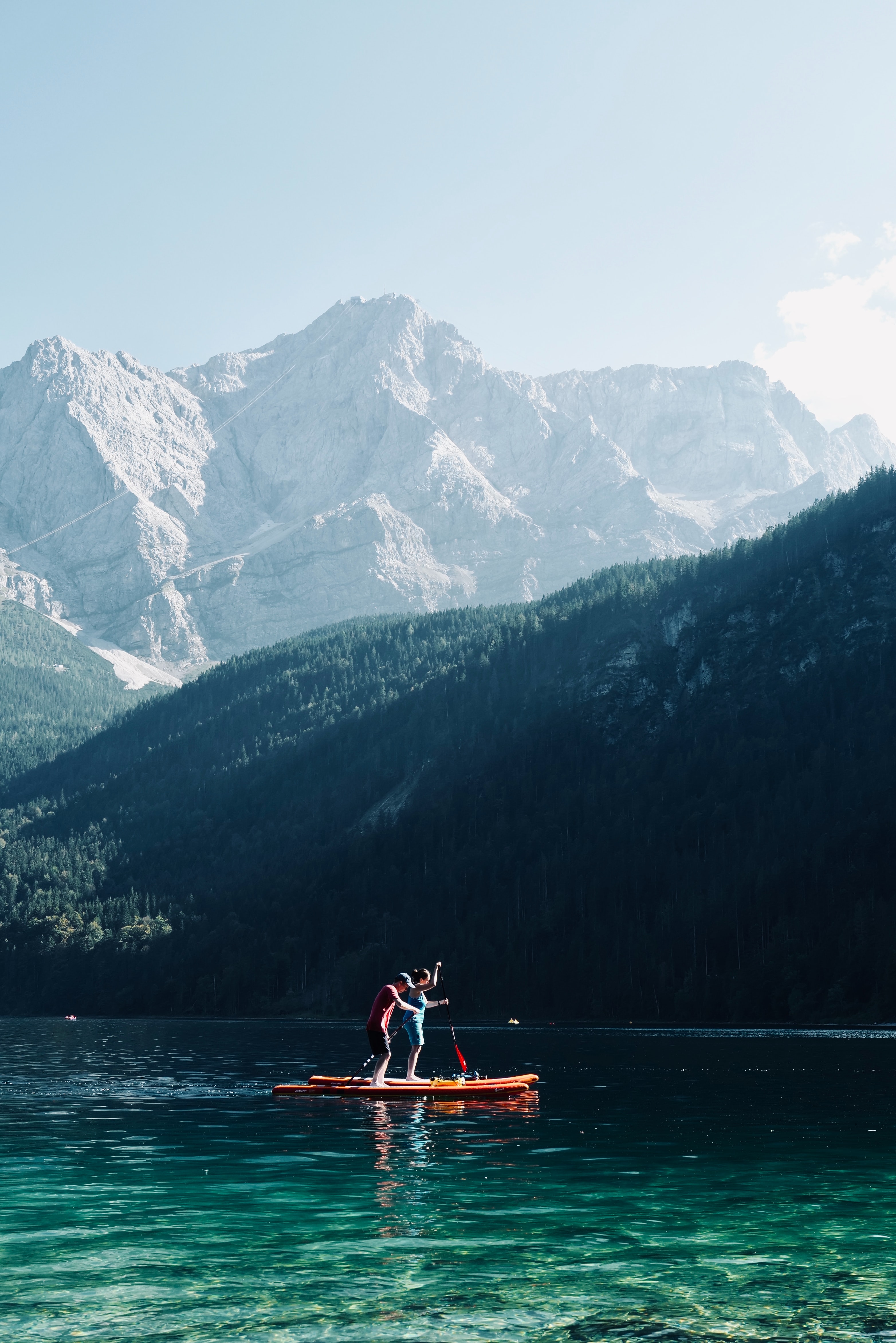 Menschen auf Stand Up Paddleboards in Wasser vor Bergkulisse