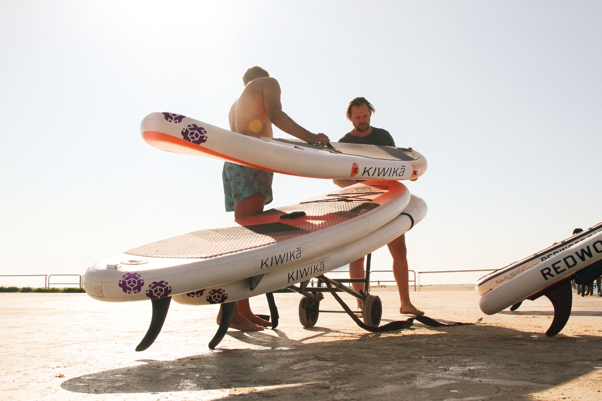 zwei MÃ¤nner mit Stand Up Paddleboards am Strand